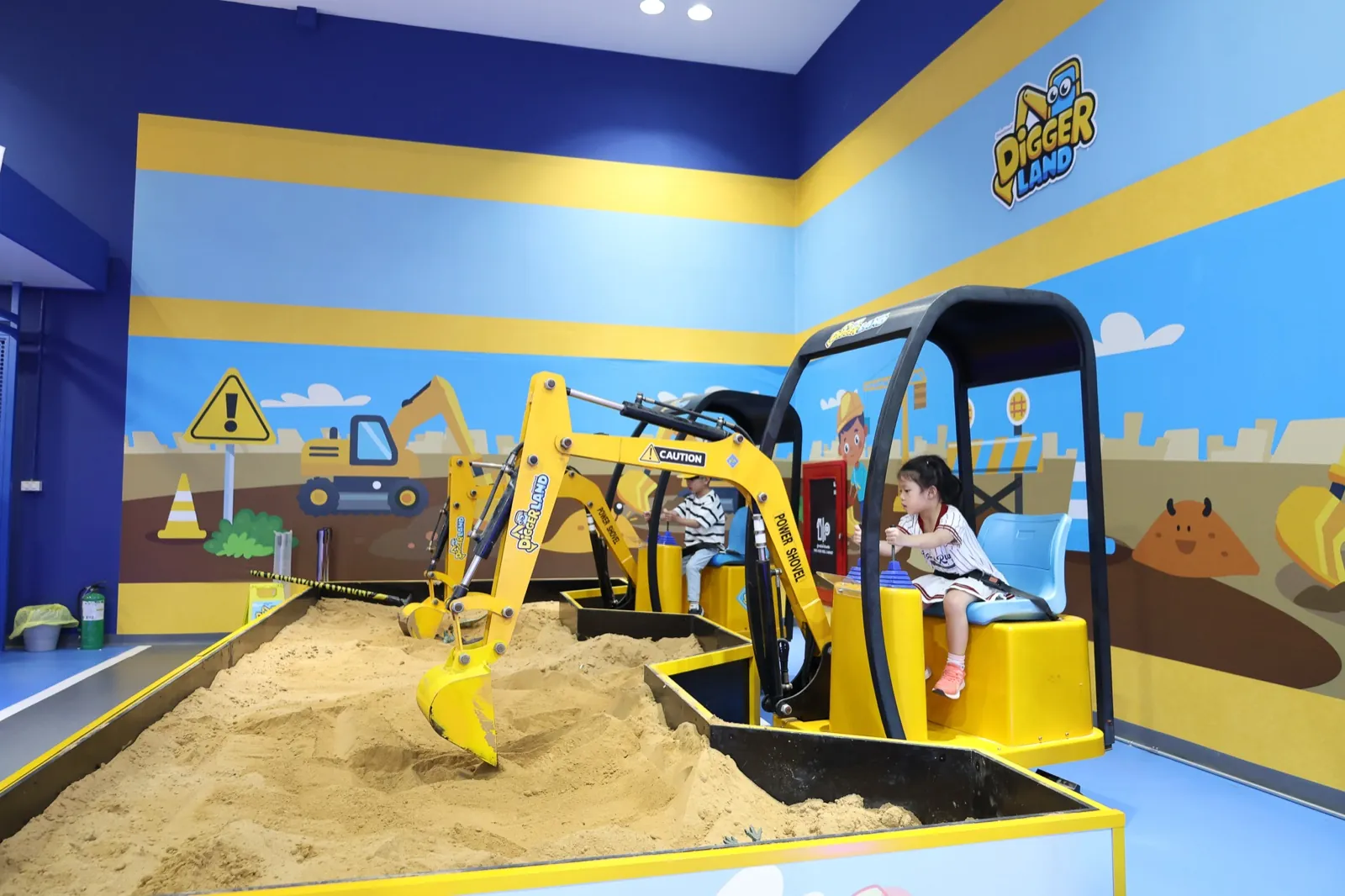 Kids driving mini excavators in the Digger Land room at The Mall Bangkae