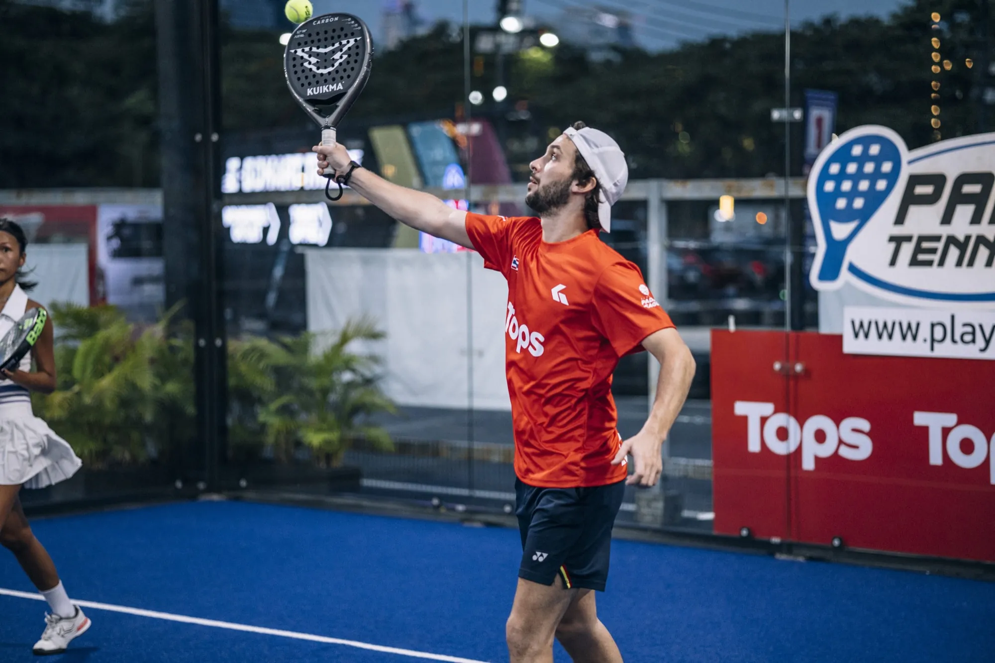 Player smashing under floodlights on the night padel court at Playerbox Chula 28